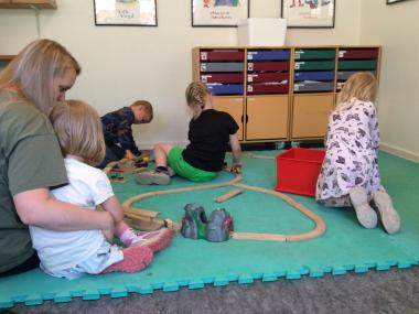 Børn bygger togbane med en voksen